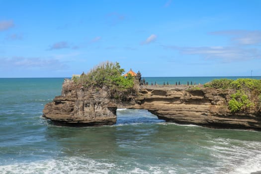 Indian Ocean coast near the Sacred Balinese temple Tanah Lot. Pura Batu Bolong on the edge of a cliff at coastline with hole in the rock. Holy place for local indonesian people
