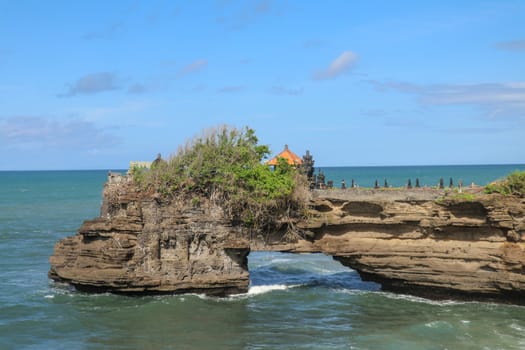 Indian Ocean coast near the Sacred Balinese temple Tanah Lot. Pura Batu Bolong on the edge of a cliff at coastline with hole in the rock. Holy place for local indonesian people