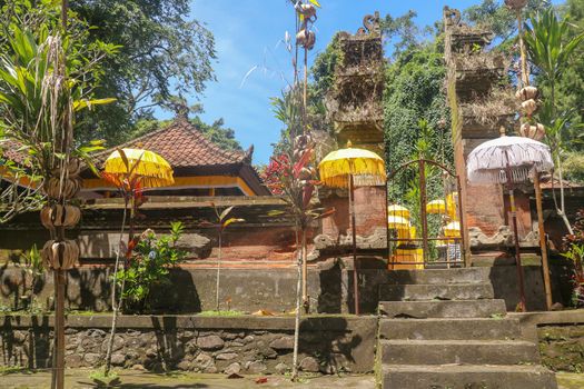 Hindu temple near to Batukaru temple on Bali island in Indonesia. Tabernacle of the Believing Balinese. Balinese culture, closeup of yellow and white decorative umbrelas among tropical plants.