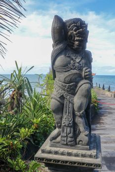 Closeup of stone statue in Temple Batu Bolong near to Tanah Lot in Bali, Indonesia. A carved statue with fine details that stands outside the entrance to Hindu temple as a guardian. Balinese culture.