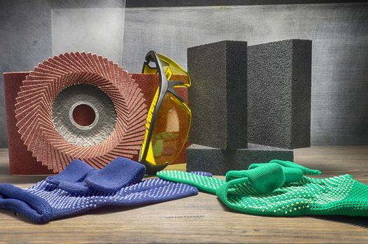 Different tools for sanding - sanding belt, abrasive sponge and flap disc for angle grinder, safety gloves and goggles, renovation, safety and health at work concept