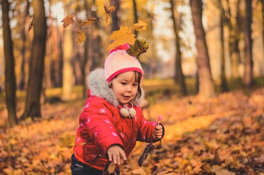 Pretty girl playing with yellow leaves in the autumn forest