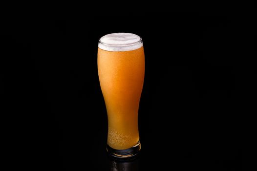 full glass Beer glassware with yellow beer and foam on an isolated black background