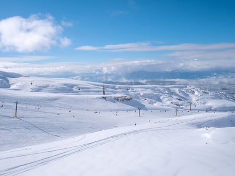 Parnassos mountain with snow and people on the slopes in a sunny day