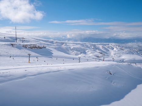 Parnassos mountain with snow and people on the slopes in a sunny day