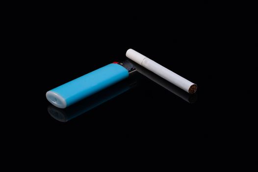 one white filter cigarette and a plastic gas blue lighter on an isolated black background with reflection