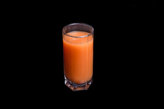 a glass of freshly squeezed fruit juice. Peach, orange or carrot on an isolated black background.