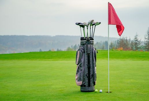 bag with golf equipment on green pitch.