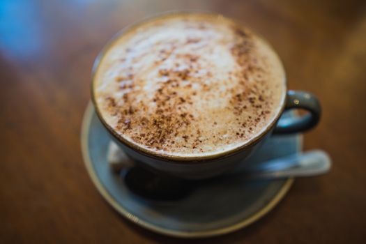 A cup of cappuccino coffee on a wooden table in a cafe setting