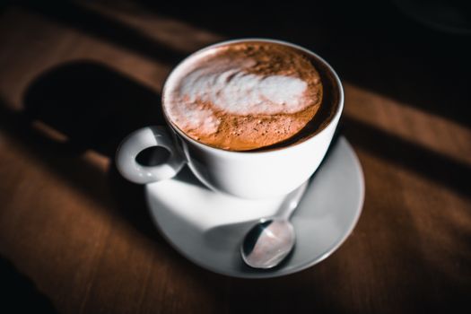 A cup of cappuccino coffee on a wooden table in a cafe setting