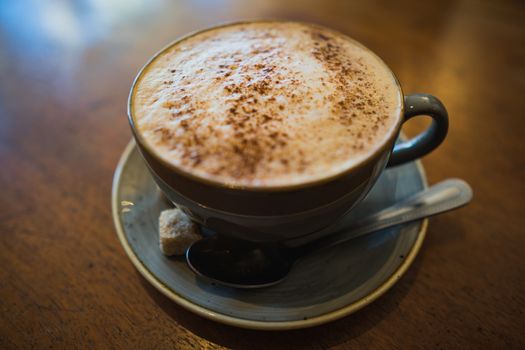 A cup of cappuccino coffee on a wooden table in a cafe setting