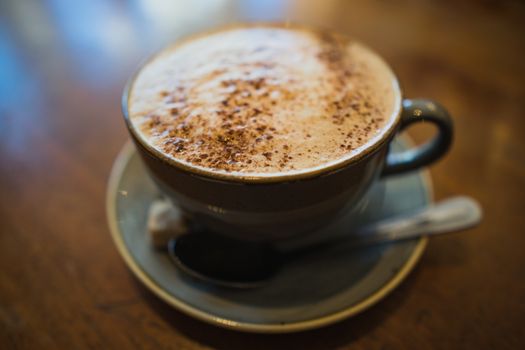 A cup of cappuccino coffee on a wooden table in a cafe setting