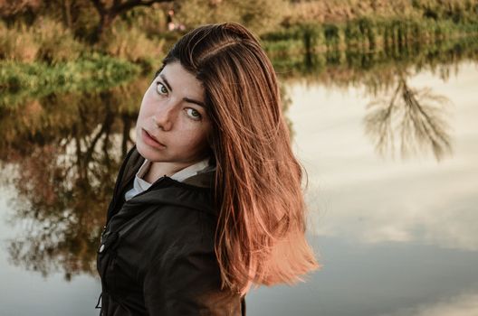 Beautiful girl standing near lake in autumn