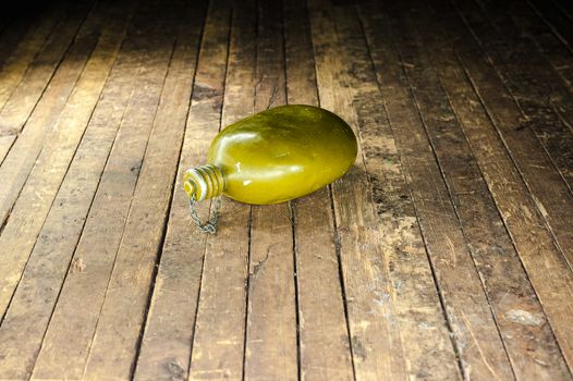 an old military canteen bottle from World War II lies on a shabby wooden floor