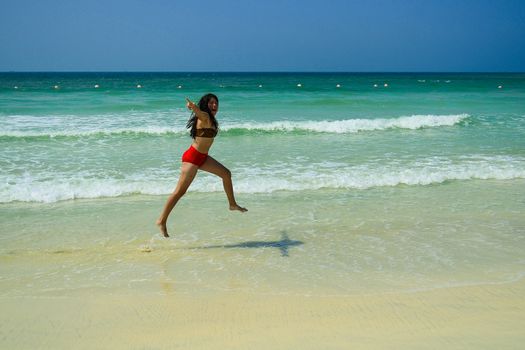 happy sexy young girl jumping on the beach by the sea.