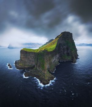 Aerial panorama of a small white lighthouse located on the edge of a huge cliff and the island of Kalsoy. Kalsoy is an isolated small island in the north-east of the Faroe Islands.