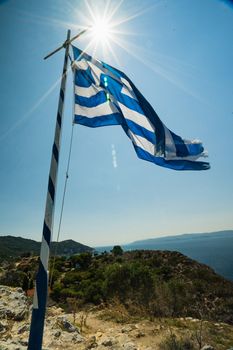 The Greek Flag in Summer on a cliff top