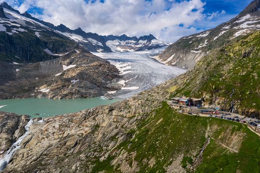 Aerial view of the melting Rhone glacier and the glacial lake, the source of the Rhone river in the Swiss Alps. It is located close to the Furka Pass and is easily accessible by road.