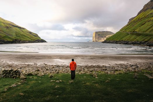 Tourist standing at the beach in Tjornuvik located on the coast of a beautiful bay in the Faroe Islands, Denmark.