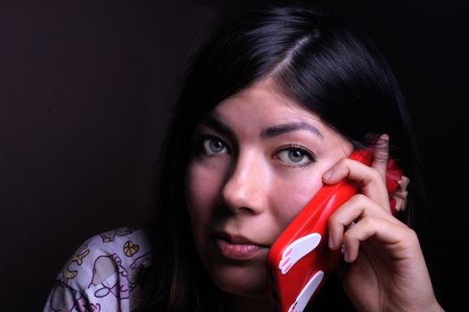 beautiful brunette girl with green eyes talking on a cell phone in a red case