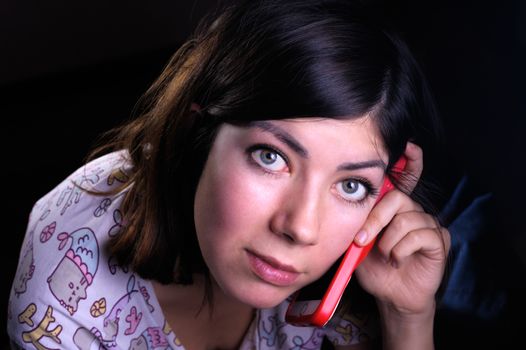 cute young woman with black hair and green eyes talking on a cell phone in a red case