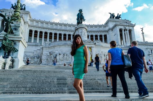 Smiling girl in a green dress stands  at the entrance to Vittorio Emanuele II Monument. Rome, Italy