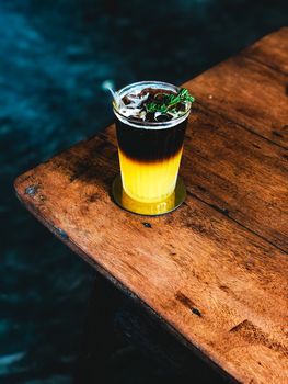 Iced fresh orange juice topped with espresso on wooden table in Modern cafe