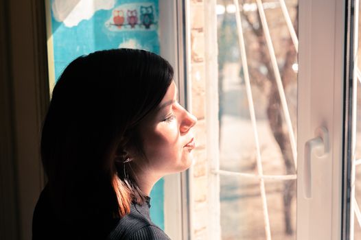 side portrait of a very cute teenager girl with black hair near the window