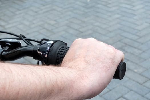 Close view of a hand on the right hand handle of a bicycle showing the gear changer