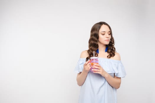 Close up portrait of attractive lovely girl in light dress handing coctail isolated on background