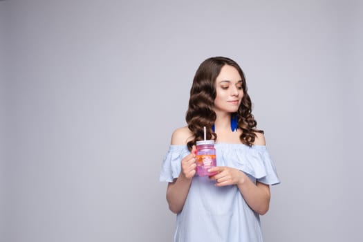 Close up portrait of attractive lovely girl in light dress handing coctail isolated on background