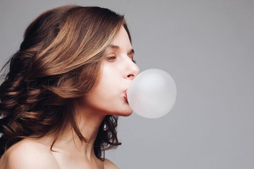 Charming young girl blowing bubble from chewing gum