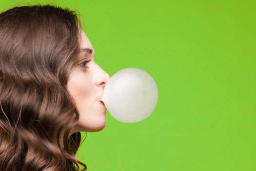 Charming young girl blowing bubble from chewing gum