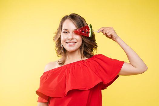 Close up portrait of attractive lovely girl in light dress handing lolipop isolated on yellow background