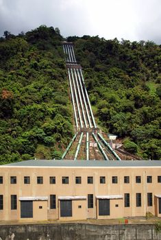 Hydroelectric plant with penstockpipes delivering water to a building housing turbines and generators
