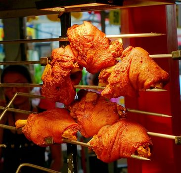 An outdoor vendor sells grilled pork knuckles or ham hock