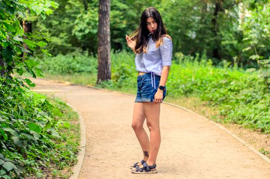 Pretty brunette girl in shorts and top on the road in park