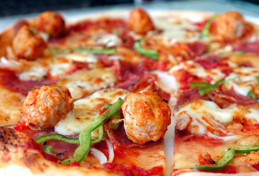 Oven baked pizza with meatballs, salami, tomatoes, cheese and fresh bell pepers
