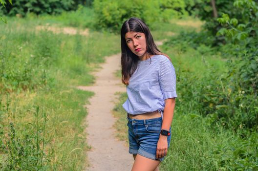 Young beauty brunette girl posing in city park