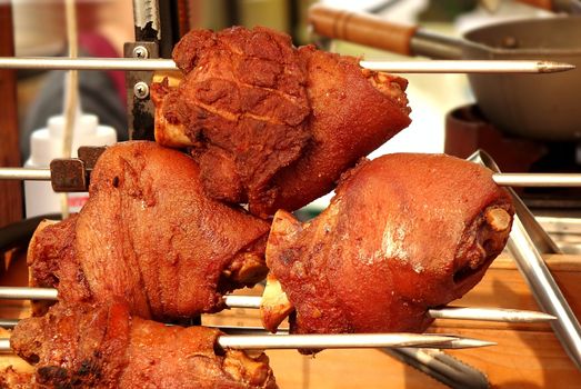 An outdoor vendor sells grilled pork knuckles or ham hock