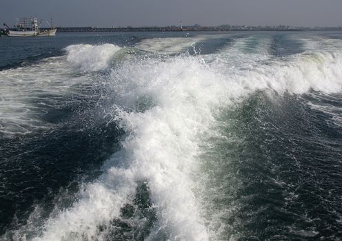 The engines of a powerful speedboat create a huge surf