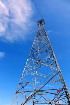 A tall high voltage electricity power mast against a blue sky