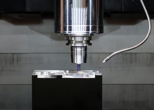 A high precision automated routing tool in operation on a piece of metal
