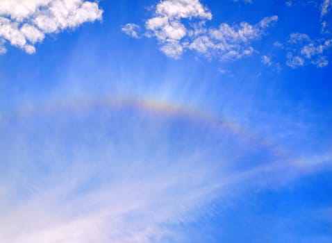 A colorful rainbow appears on a clear blue sky
