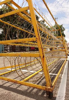 A yellow painted metal barrier with razor wire is used to guard a military installation