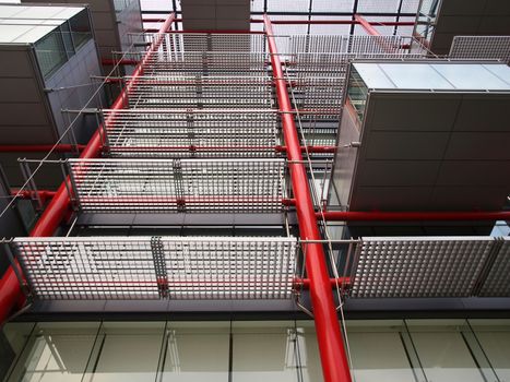A modern building facade with red pipes and steel gratings
