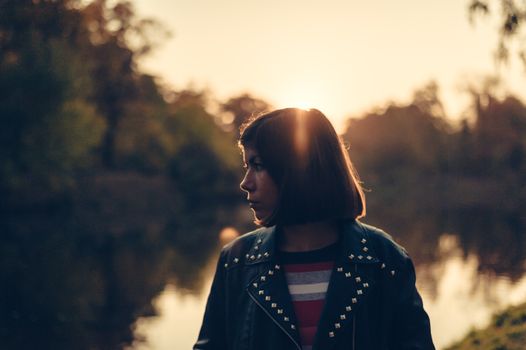 young girl in profile at dusk near a lake in a park