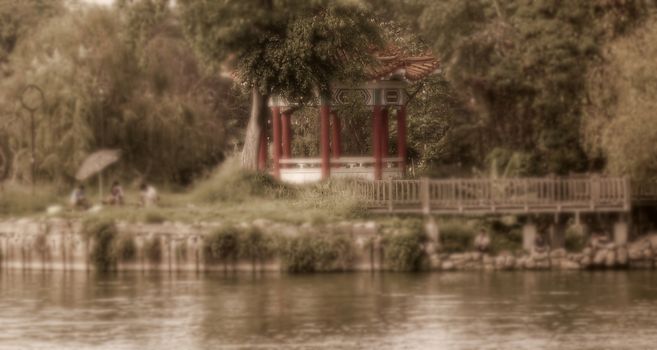Vintage style image with selective focus of people relaxing by the lakeside in the heat of summer
