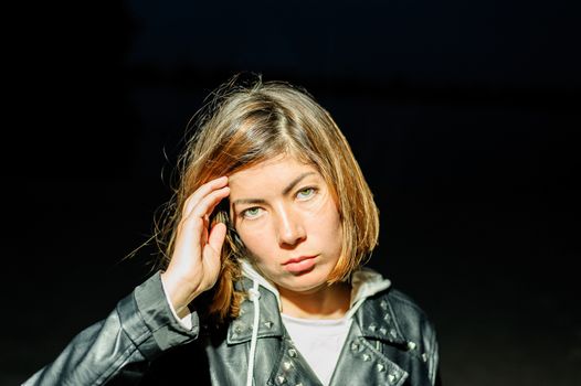 Close-up portrait of a cute young woman who holds hands near her forehead