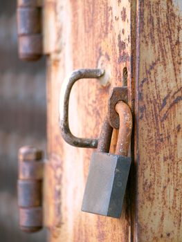 A rusty old padlock on a corroded iron door
